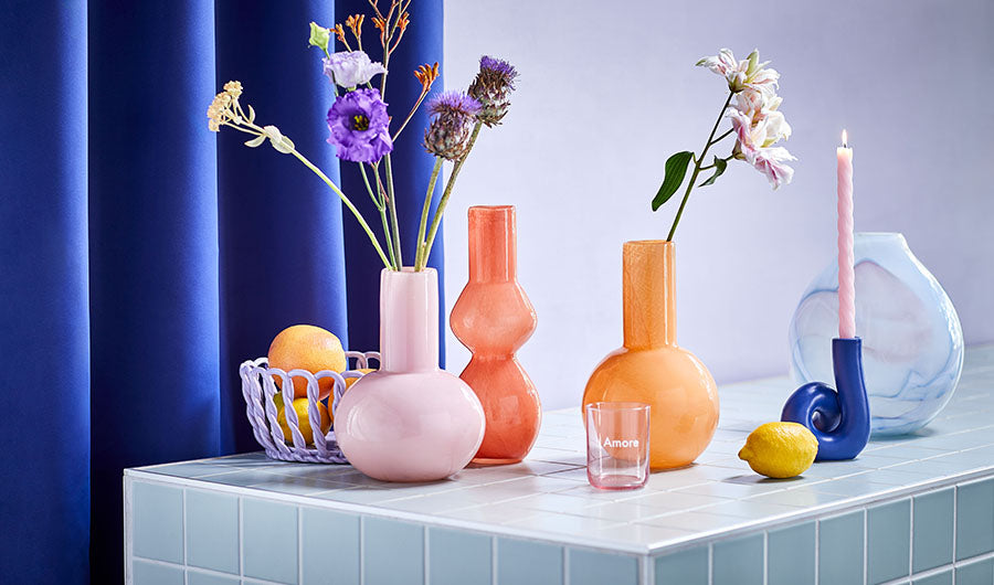 Bunte Glasvasen in Rosa Orange und Blau auf Fliesentisch