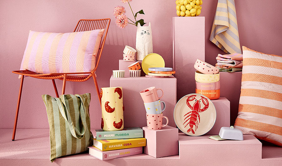 Bunte Butlers-Produkte auf rosa Hintergrund mit Hummerteller und Katzenvase