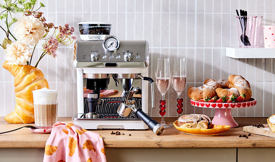 Espressomaschine mit Croissants und Champagnerglas auf Holztheke