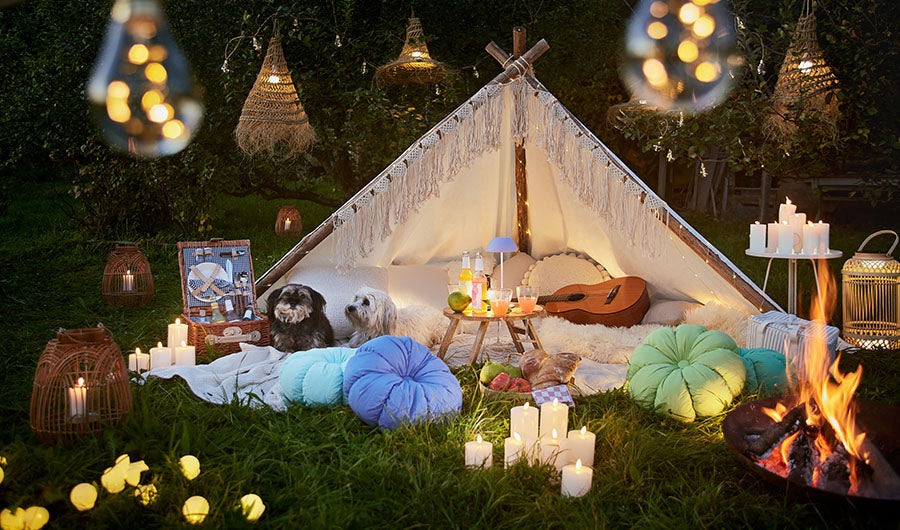Weißes Tipi-Zelt mit Hunden und Lichterketten im nächtlichen Garten