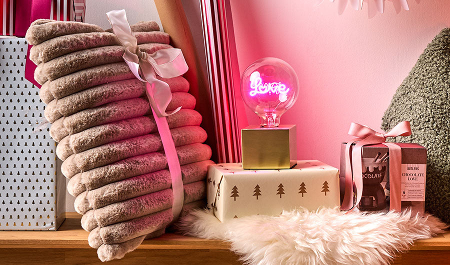 LED-Kugellampe Love neben rosa Decken und Geschenken