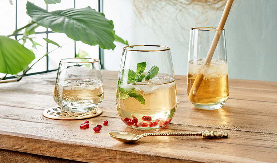 Longdrinkgläser mit Goldrand und Minze auf rustikalem Holztisch