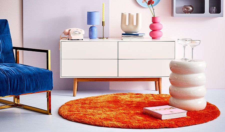 Retro-Wohnzimmer mit blauem Samtsessel und orangem Teppich