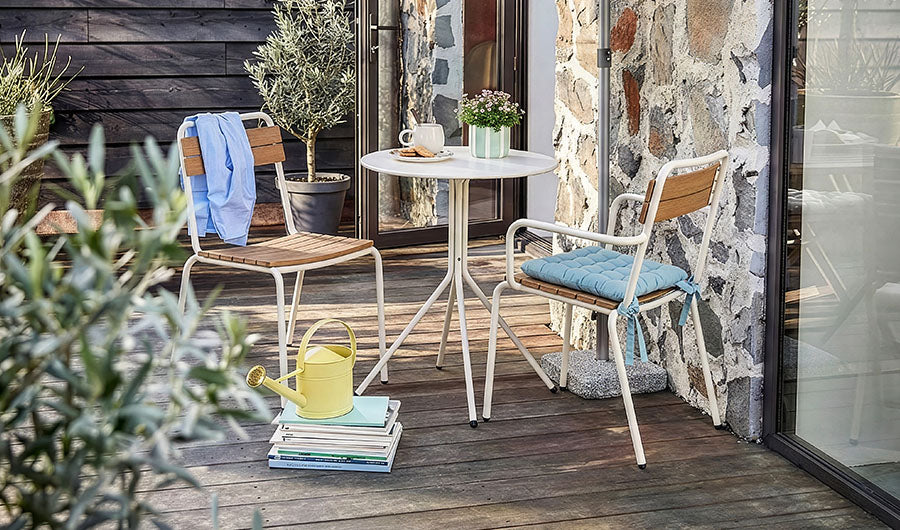 Helle Outdoormöbel mit Tisch auf Holzterrasse neben Olivenbaum