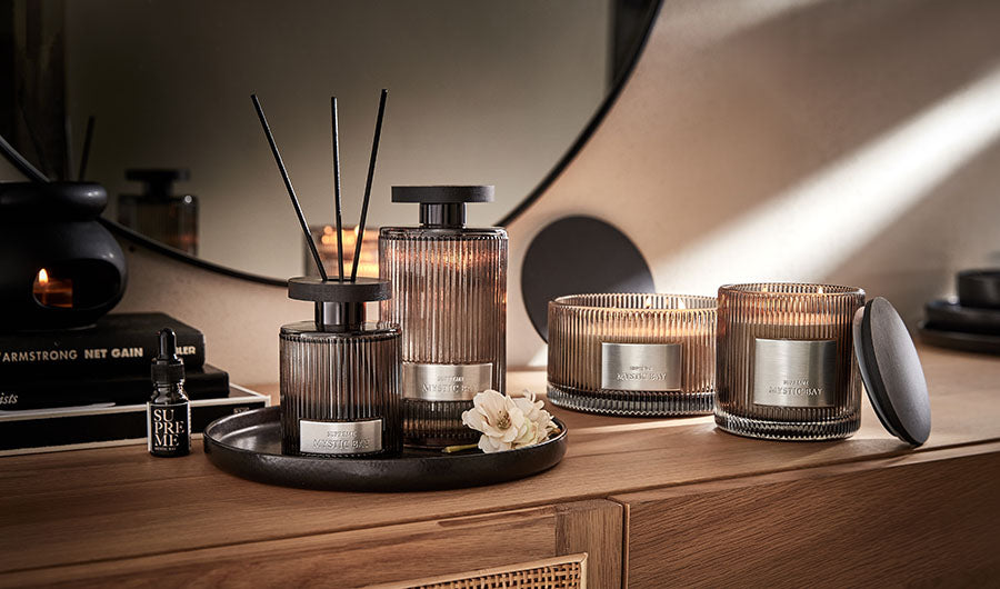 Raumduft-Diffuser mit Kerzen auf dunklem Holzsideboard