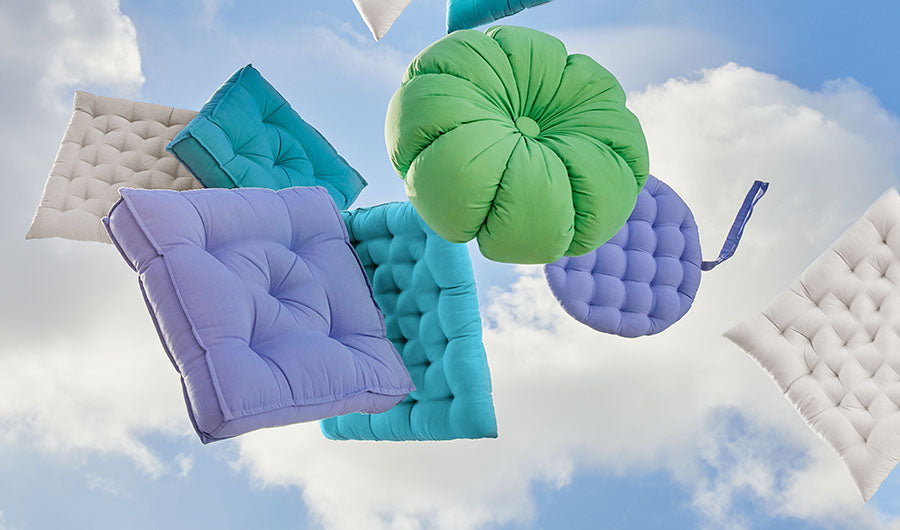 Bunte Stuhlkissen in Lila, Türkis und Grün vor Himmel