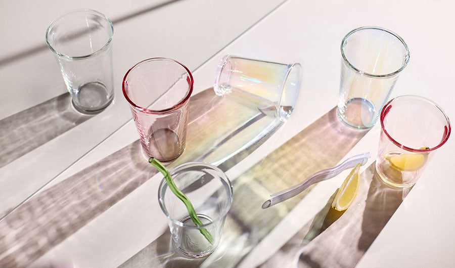 Bunte Wassergläser in Rosa und Grau im Sonnenlicht