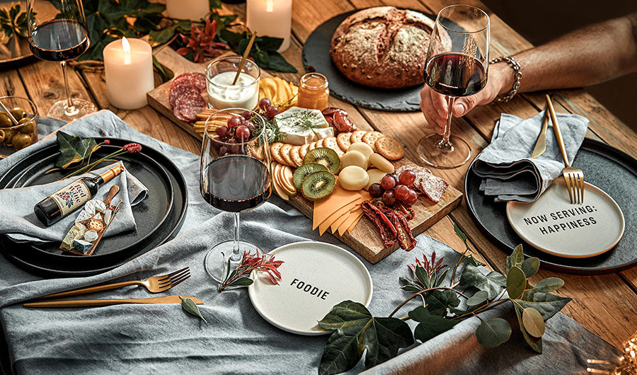Dunkles Steinzeuggeschirr mit Käseplatte und Rotwein festlich gedeckt