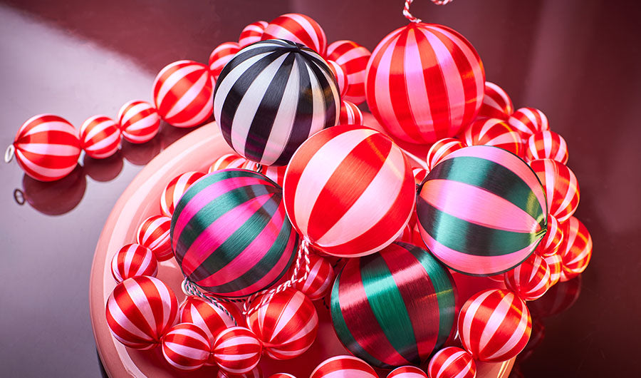 Gestreifte Weihnachtskugeln in Rot Pink und Grün auf Schale