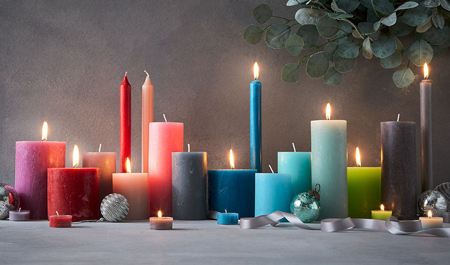 Brennende bunte Adventskerzen mit Eukalyptus und silbernen Weihnachtskugeln