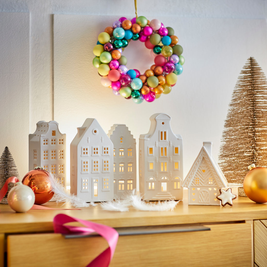 Weiße Porzellan-Lichthäuser mit buntem Kugelkranz auf Sideboard