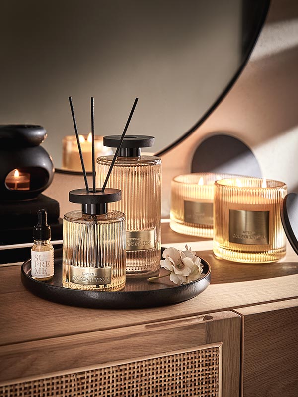 Golden Riviera Raumduft-Serie mit geriffelten Glas-Flakons, Duftkerzen und Aroma-Öl auf einem schwarzen Metallteller im eleganten Vintage-Design.