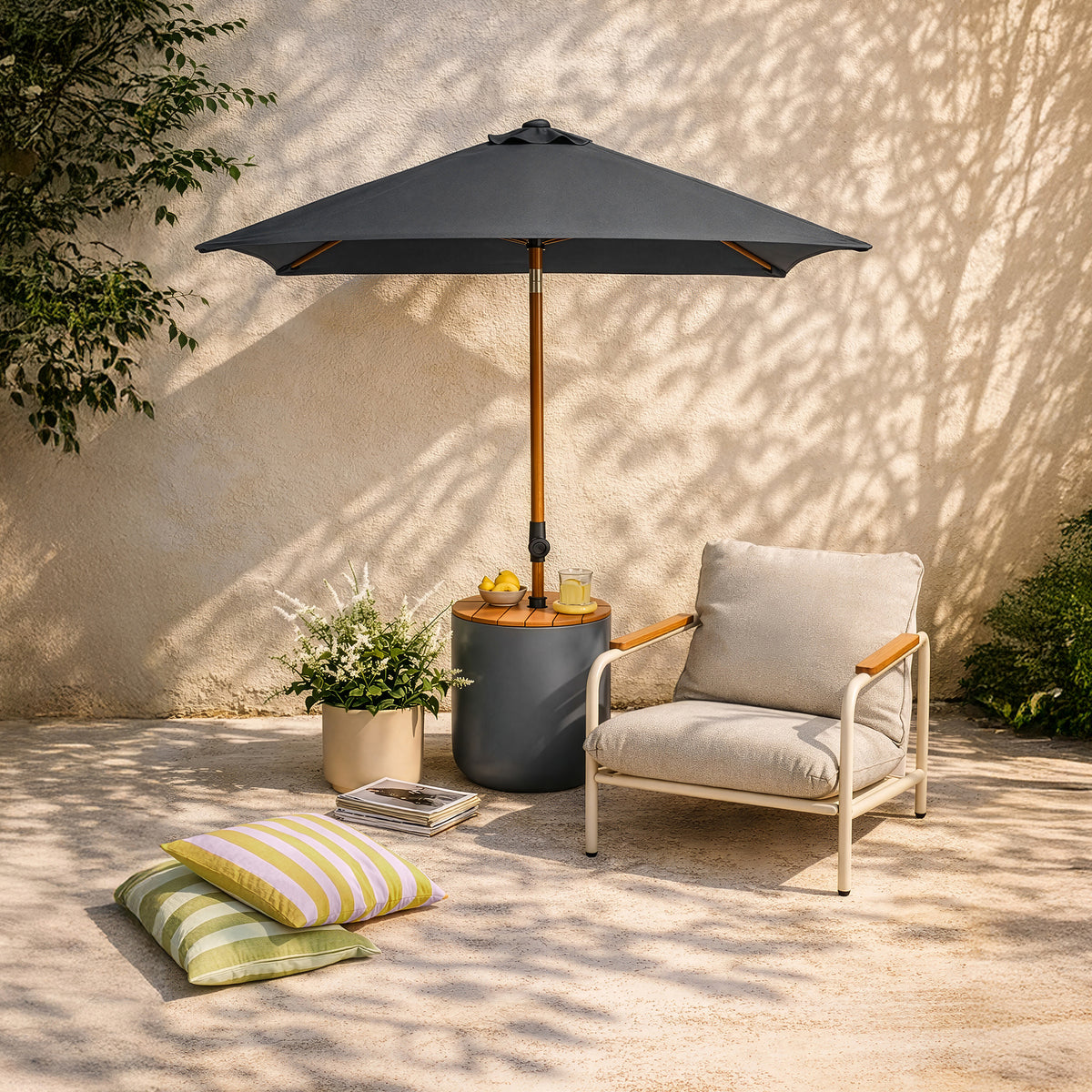 Ein grauer Sonnenschirm mit Holzmast steht in einem runden Schirmständer auf einer sonnigen Terrasse neben einem gemütlichen Loungesessel und bunten Outdoorkissen.