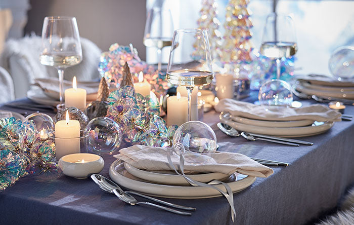 Winterliche Festtafel mit irisierenden Kugeln und Kerzen