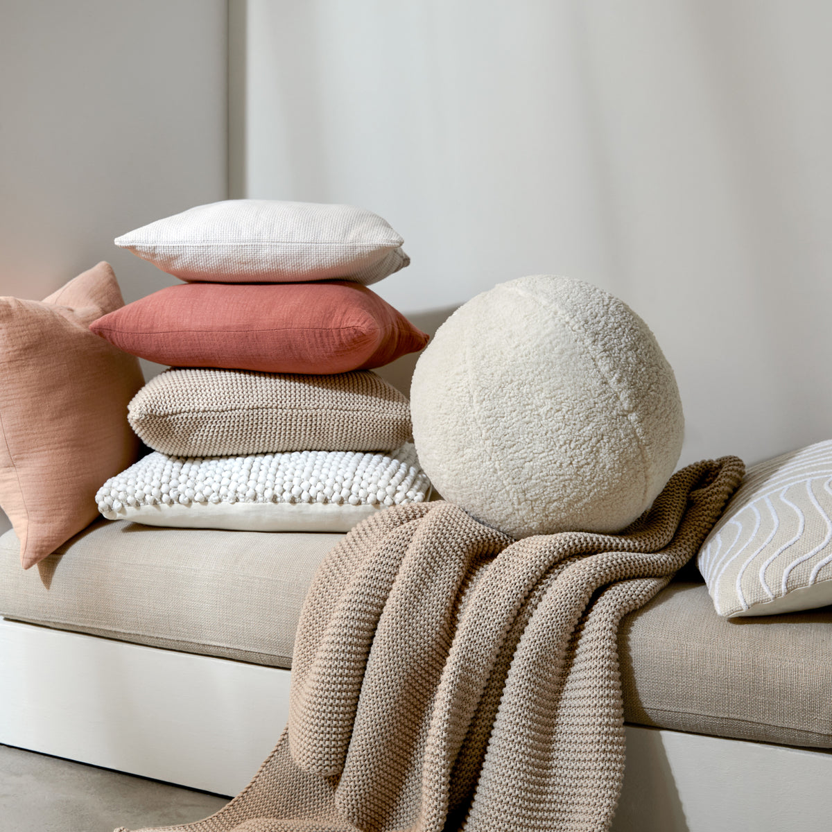 Mehrere Kissen und Decken in beige und braun.