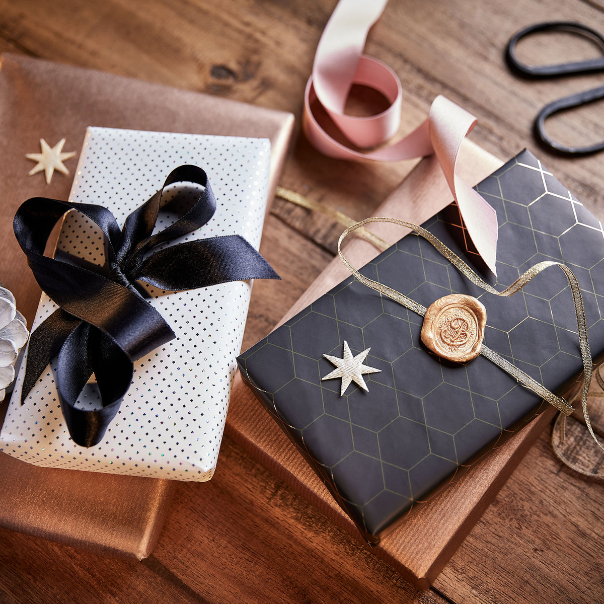 Festlich verpackte Geschenke mit Satinbändern und Siegel auf Holz