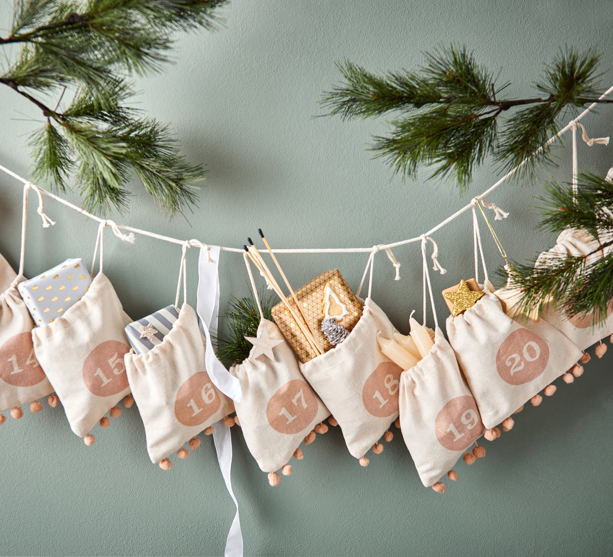 Adventskalender aus Stoffsäckchen mit Pompons an einer Schnur