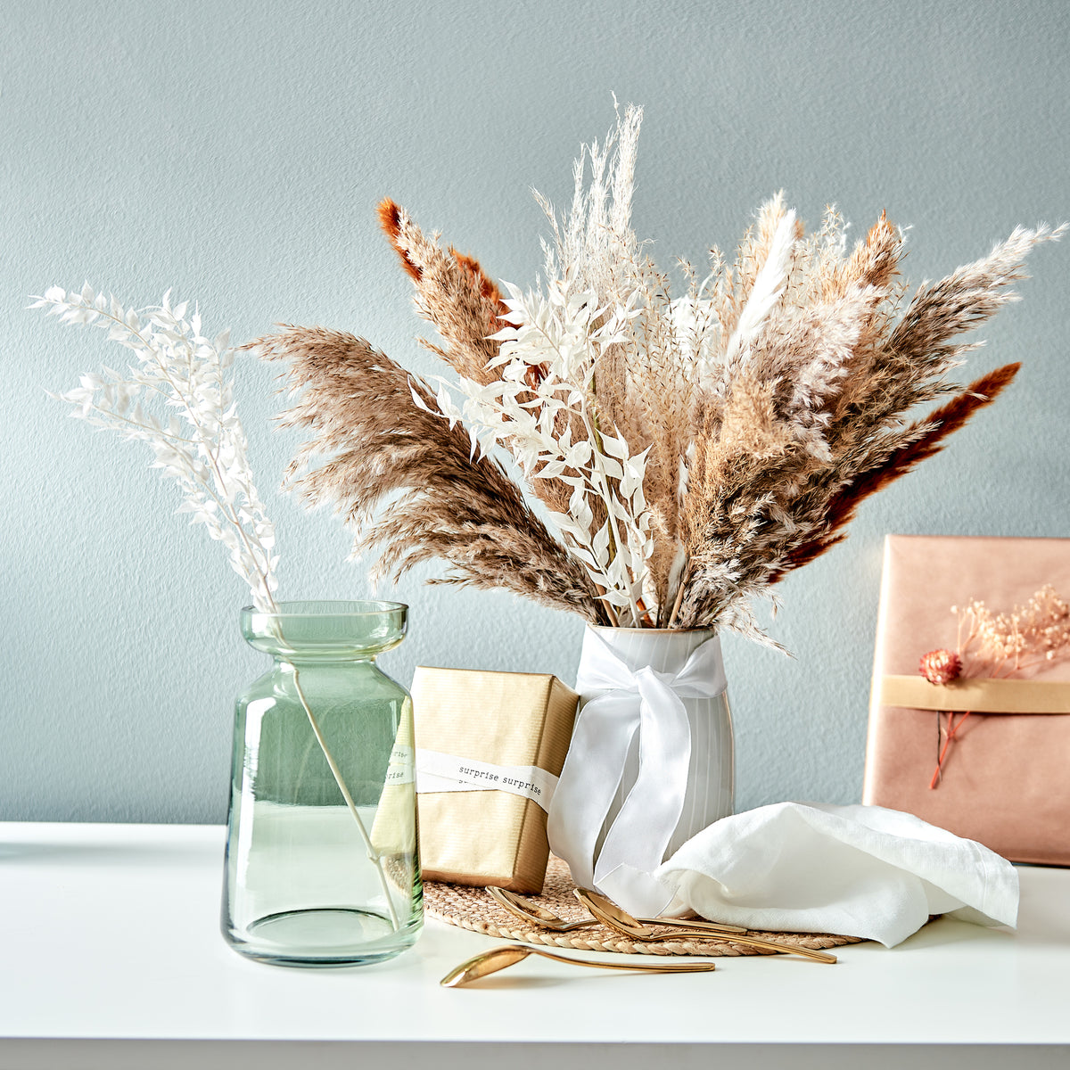 Trockenblumen in Vasen mit hübsch verpackten Geschenken