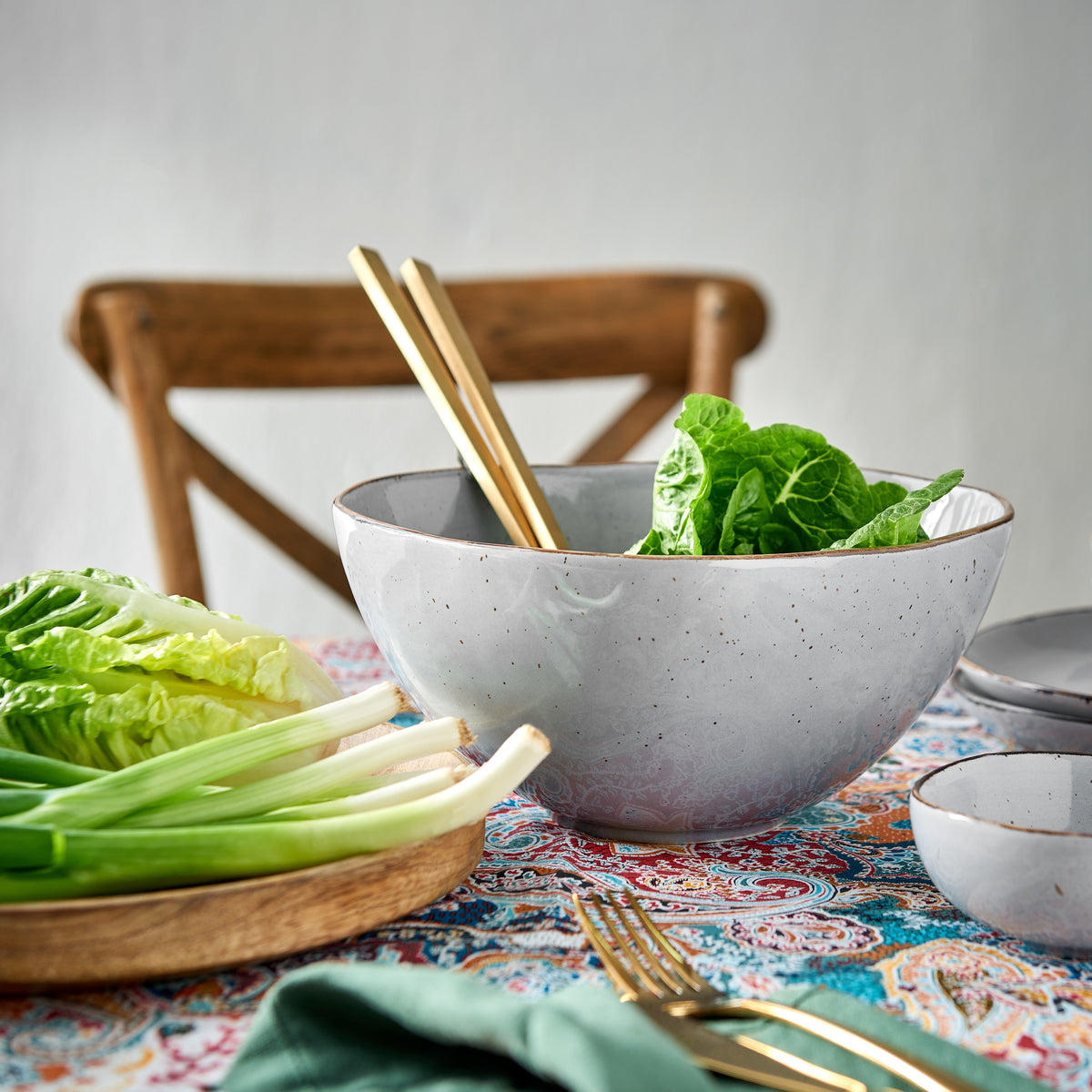 Helle Steinzeug-Salatschüssel mit goldenem Salatbesteck und Römersalat