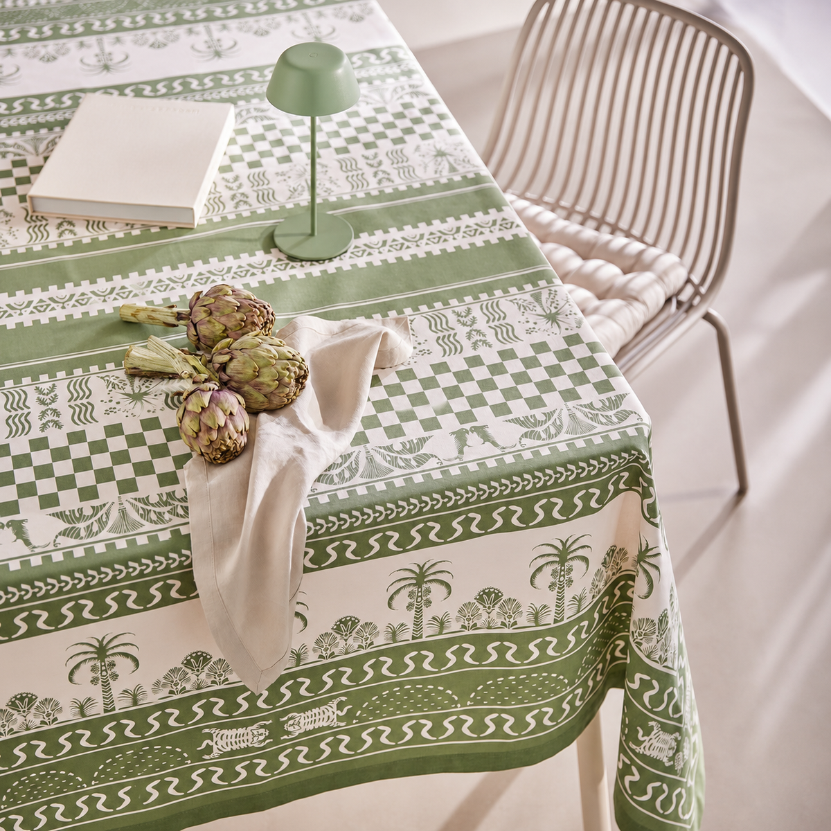 Grün gemusterte Tischdecke mit Stoffserviette auf gedecktem Tisch