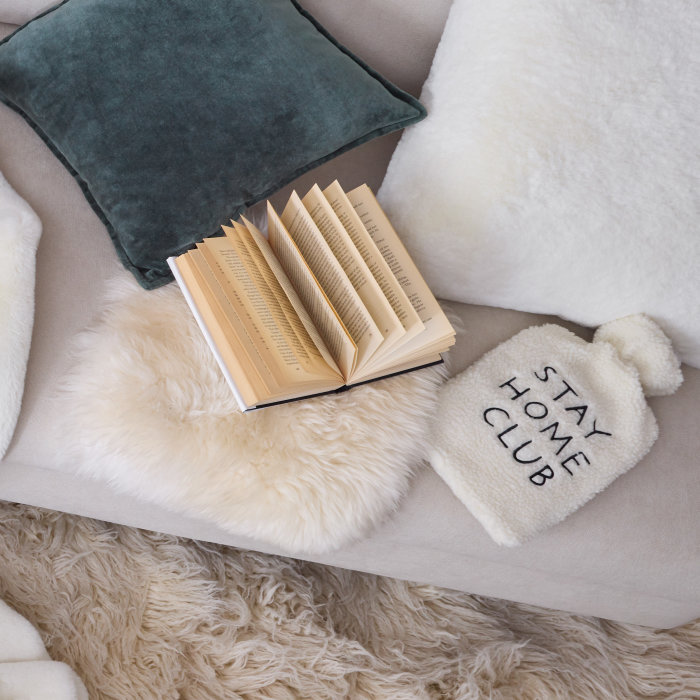 Wärmflasche Stay Home Club auf gemütlichem Sofa