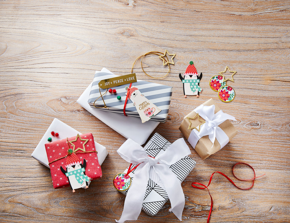 Bunt verpackte Weihnachtsgeschenke mit Anhängern und Deko auf Holztisch