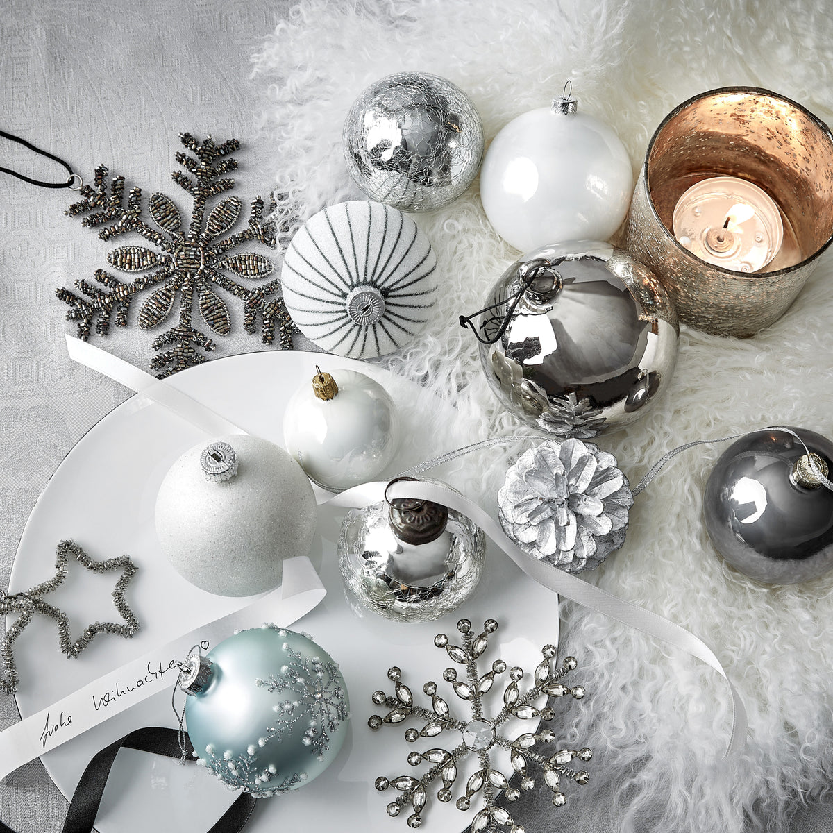 Weihnachtskugeln in Weiß und Silber mit Schneeflocken und Windlicht